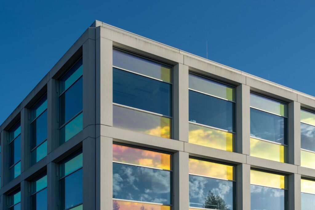 Modern building facade with reflective glass against a clear blue sky, showcasing architectural design.